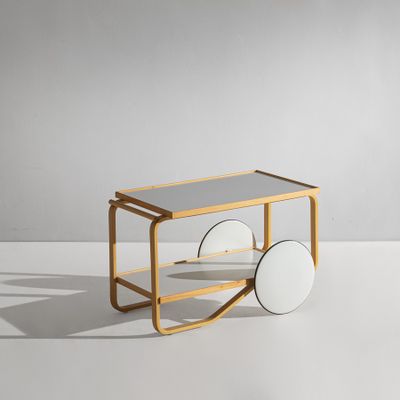 une petite charrette en bois à deux roues posée sur une surface blanche