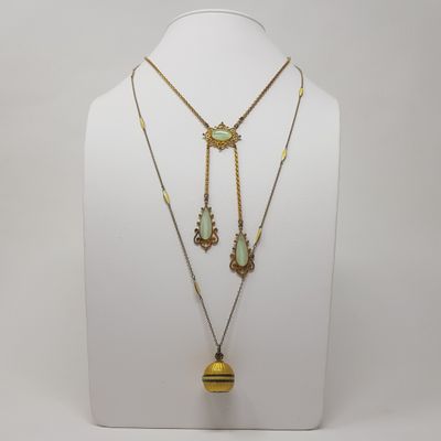 a white mannequin with two necklaces and a pendant