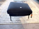 un pouf noir posé sur un tapis dans une pièce