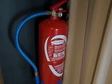 un extincteur rouge fixé à un mur noir