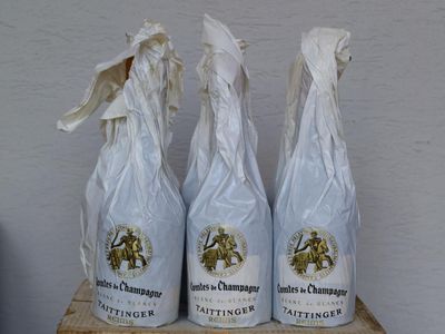 trois bouteilles de vin posées sur une caisse en bois