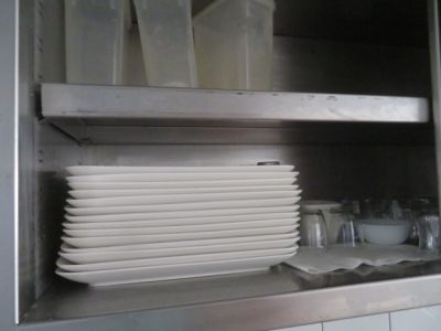 quelques assiettes blanches sont empilées sur une étagère dans une cuisine