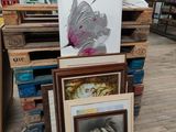une pile d'œuvres d'art encadrées posées par terre dans un magasin