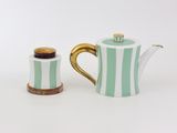 une petite théière et une autre petite théière posées sur une surface blanche