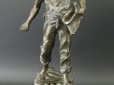 statue en bronze représentant un homme tenant un sac, posée sur un socle en marbre