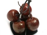 four cherries sitting on a black plate on a white surface