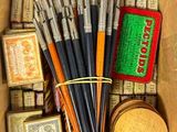une boîte remplie de différentes sortes de peinture et de pinceaux