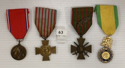 trois médailles et une croix sont exposées sur un socle blanc