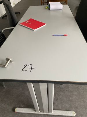une table blanche avec un cahier rouge et une chaise noire