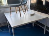 une table blanche avec deux chaises, placée devant une fenêtre