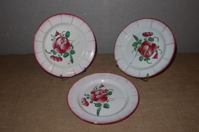 trois assiettes ornées de roses, posées sur une table