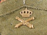 a green hat with a crown and two crossed swords on it