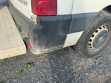 une camionnette blanche avec un pneu crevé, garée sur un parking