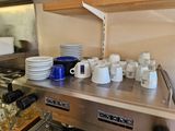 many cups and mugs sitting on a shelf in the kitchen