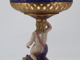 a blue and gold vase with a woman sitting on it