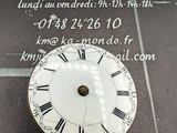 une horloge dont le cadran porte des chiffres romains, posée par terre