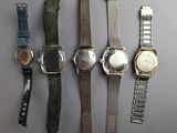 several watches are lined up on a table with a gray background