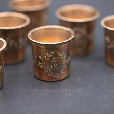 six gold cups with designs on them are lined up on a table