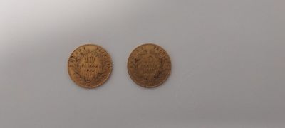 two gold coins sitting on top of a white surface next to each other
