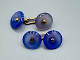 deux paires de boutons de manchette en verre bleu et blanc posés sur une surface blanche
