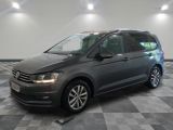 une Volkswagen Touran grise garée dans un garage au sol carrelé