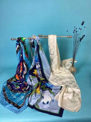 three scarves hanging on a rack on a blue background
