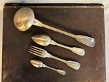 five silver spoons and two silver spoons on a brown tray
