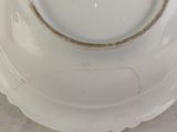 an old white plate sitting on top of a table next to a cup