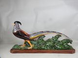 statue of a pheasant on a wooden base on a white background