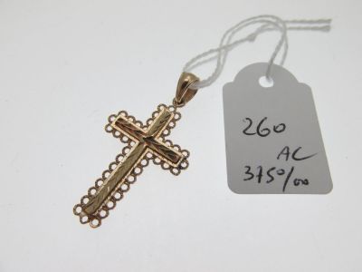 une petite croix en or posée sur une table blanche, avec une étiquette de prix