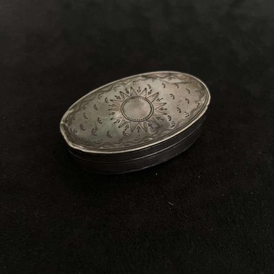 a silver box with a clock on it on a black surface