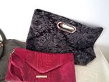 two purses and a handbag sitting on a bed