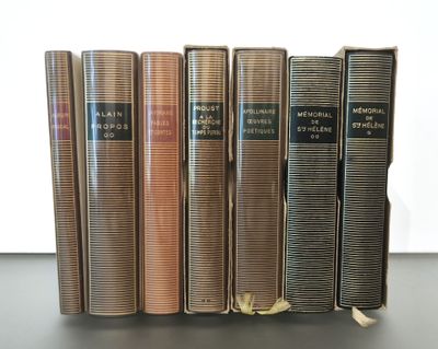 Quatre livres sont alignés sur une table, avec un mur blanc en arrière-plan.