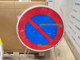 a red and blue no parking sign in front of a cardboard box