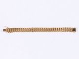 a close up of a gold bracelet on a white surface