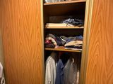 an image of a closet with clothes hanging on the shelves