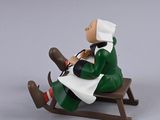 toy figurine of a woman sitting on a sled with a dog