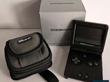 une petite Game Boy noire posée à côté d'un étui noir