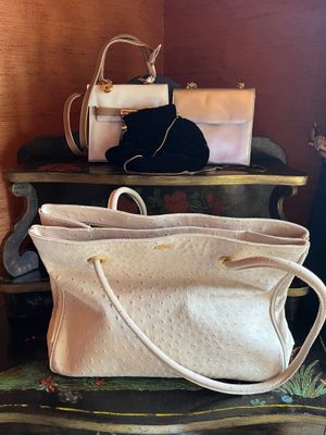 a white purse sitting on top of a stack of suitcases