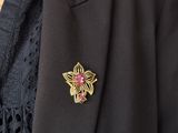 a close up of a black jacket with a pink flower pin on it