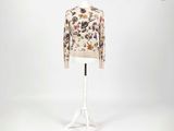 un mannequin blanc portant un pull à motifs floraux, posé sur un socle blanc