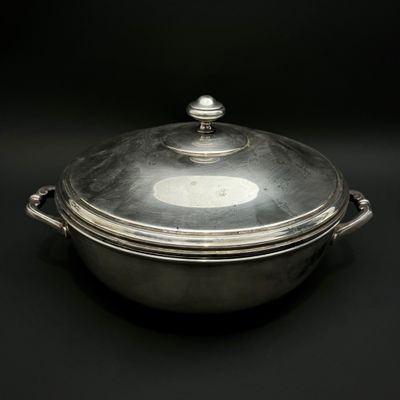 une cocotte ancienne en métal argenté avec un couvercle, sur fond noir