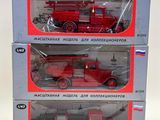 three red firetrucks in boxes on a white surface