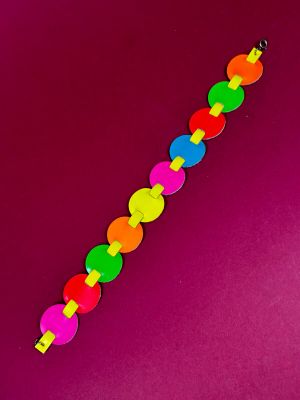 a close up of a colorful bracelet on a pink surface