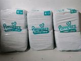 quatre paquets de couches Pampers empilés les uns sur les autres