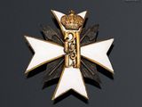 a close up of a white and gold cross with a crown on it