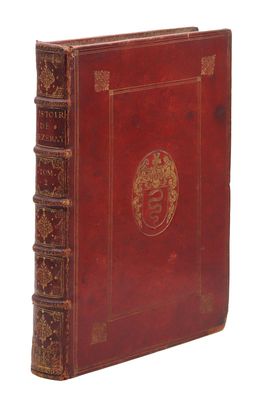 un vieux livre rouge avec un emblème doré sur la couverture