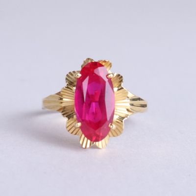 une image d'une bague en or avec une pierre rose au centre