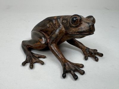 statue d'une grenouille assise sur une surface blanche