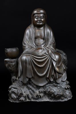 statue of a buddha sitting on a rock with a bowl in his hand